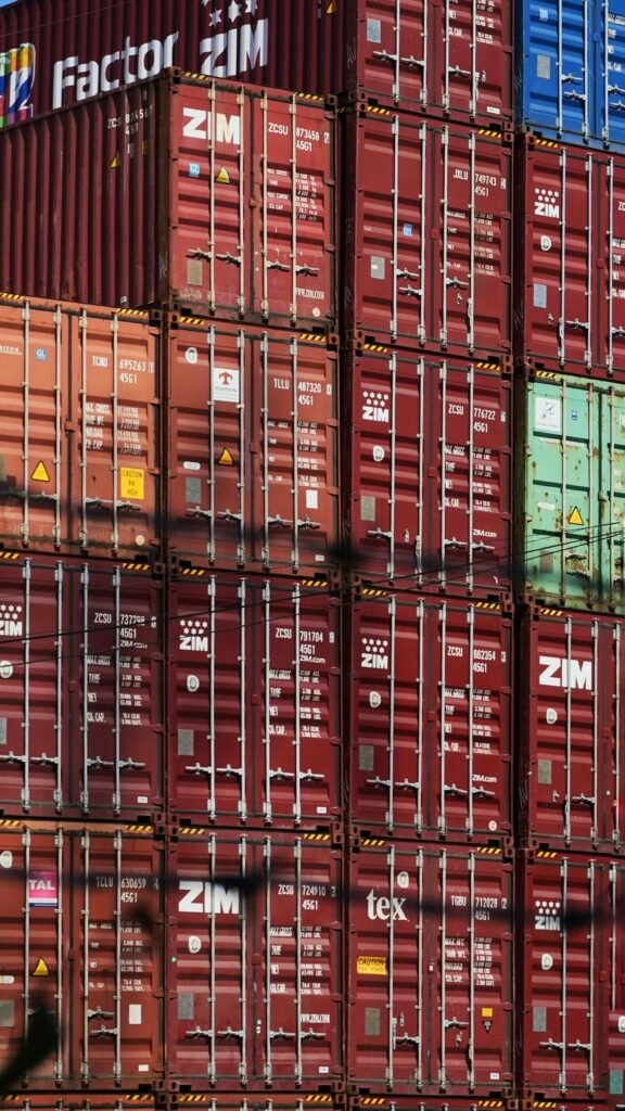 pexels photo 13600203 13600203 Vertical shot of colorful, stacked shipping containers at a bustling cargo port.